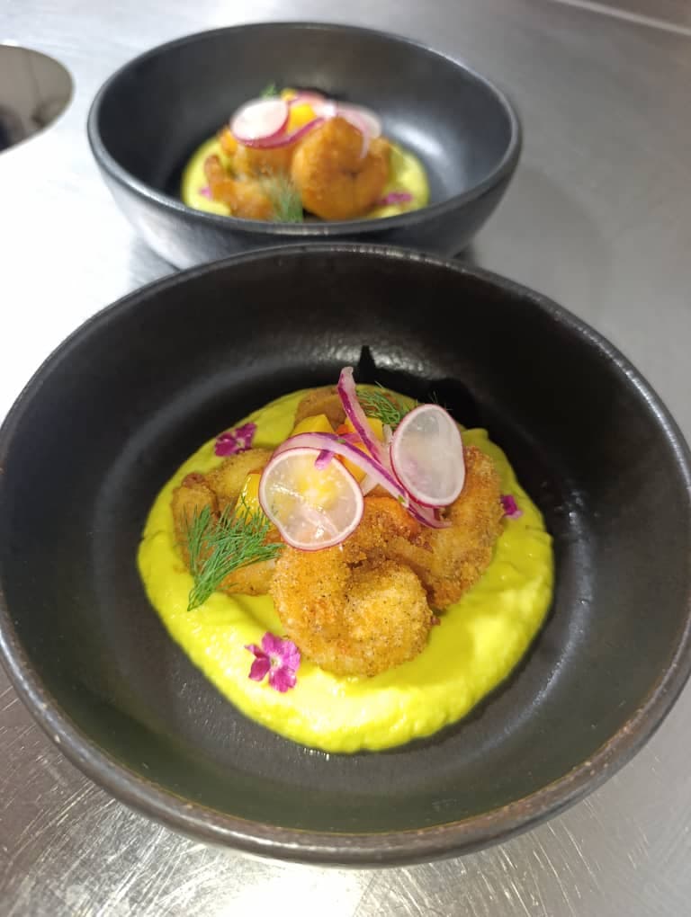 Camarones empanizados sobre crema de cúrcuma con flores